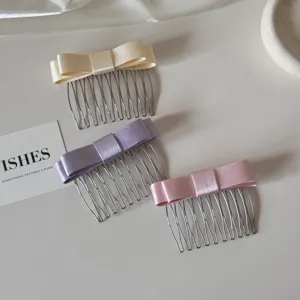 Close-up view of three elegant satin bow hair combs in cream, lavender, and pink colors