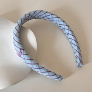 Detail view of a blue and purple plaid checkered headband with a sweet cherry charm.