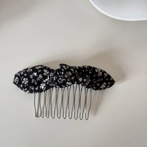 Close-up of retro floral bow hair comb with black fabric on white background