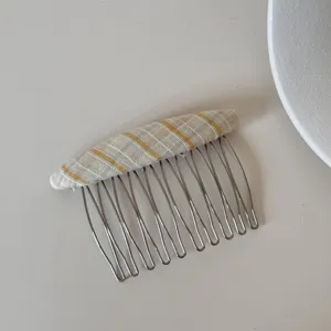 Vista dettagliata del pettine per capelli in tessuto a righe gialle e grigie elegante