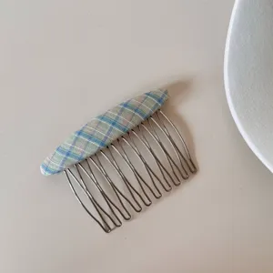 Dettaglio di un pettine per capelli minimalista in tessuto scozzese per acconciature chic.