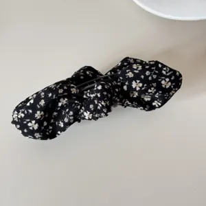 Close-up of retro floral bow hair clip with black fabric and white flower pattern