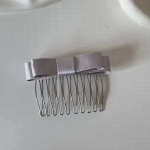 Macro detail of a lavender satin bow hair comb featuring elegant metal teeth design