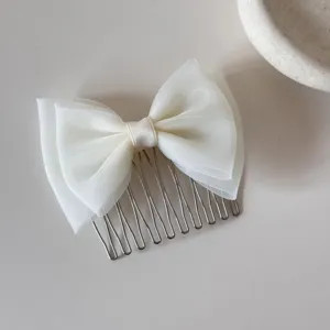 Detailed macro view of a sweet white mesh bow hair comb for girls featuring silver metal tines