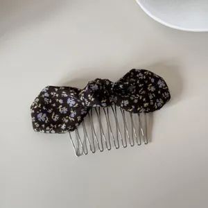 Detailed view of a vintage style floral print bow hair comb featuring silver metal teeth