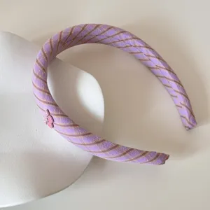 Close-up view of purple plaid fabric headband with a pink heart charm detail