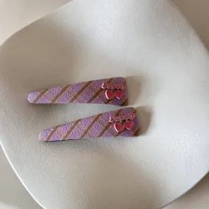 Detail of purple plaid hair clips featuring cute pink cherry decorations and Sweety text.