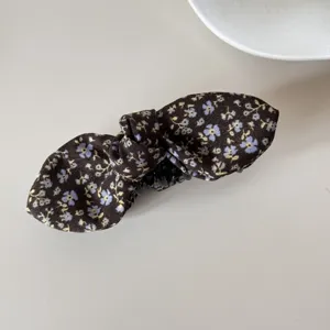 Close-up detail of the vintage floral print on a dark fabric bow hair clip accessory