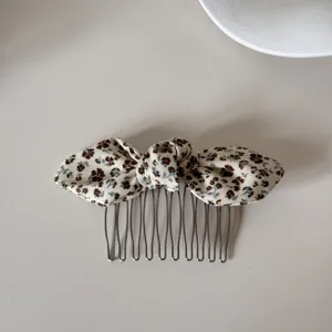 Detailed view of a vintage floral print fabric bow hair comb with metallic teeth accessory.