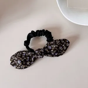 Detailed macro view of a retro floral bow scrunchie with elegant blue flower patterns