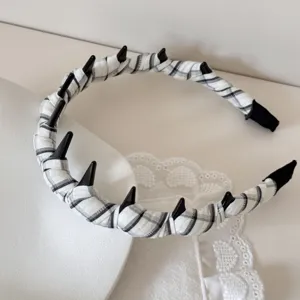 Detail shot of a black and white checkered headband with stylish gothic black spikes.