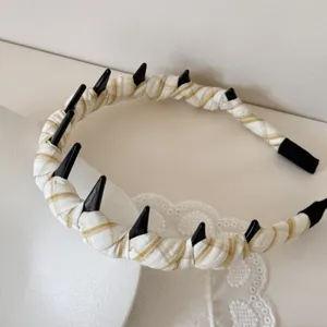 Close-up of plaid wrapped headband with black spikes and lace detail