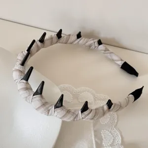 Detailed view of a stylish plaid fabric wrapped headband with black decorative spikes