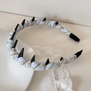 Close-up detail of light blue plaid fabric toothed headband on lace background