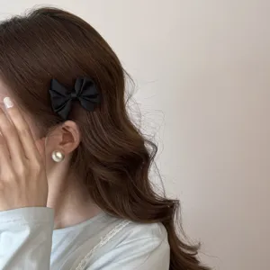 Détail d'une élégante pince à cheveux en satin noir portée par un mannequin avec style