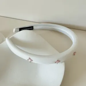 Diadema acolchada blanca con lazos rosas y strass para un efecto de cráneo elevado