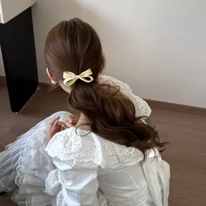Élastique à cheveux élégant avec nœud en tissu crème et pois sur une mannequin
