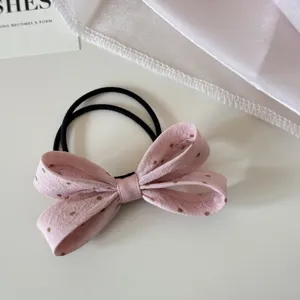 Gros plan détaillé d'un chouchou à nœud en tissu rose à pois sur une surface blanche