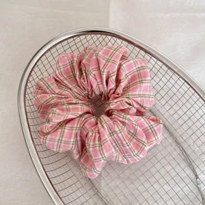 Vue détaillée d'un chouchou à carreaux roses avec texture froncée douce dans un panier en métal