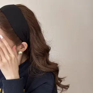 Side view of a thick black ribbed headband on long wavy hair for elegant styling.