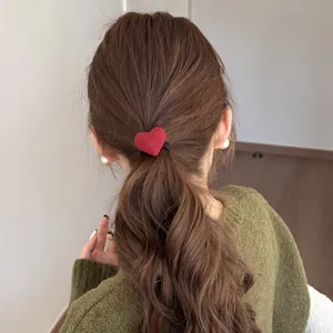 Detailed rear view of a ponytail styled with a soft red plush heart-shaped hair tie.