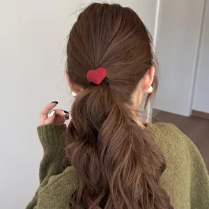 Rear view of model with a plush red heart hair tie on a wavy ponytail hairstyle.