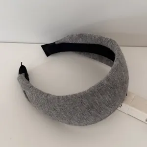 Close-up of a thick grey knitted headband featuring a cozy wool-like texture.