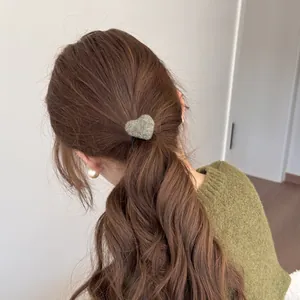 Close-up of a model wearing a green fuzzy heart-shaped hair tie on a stylish ponytail.