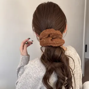 Detailed shot of a brown plush hair scrunchie used on a low ponytail hair styling