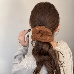Detailed back view of a model wearing a cozy brown plush felt scrunchie in a low ponytail