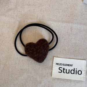 Close-up detail of a soft brown fuzzy heart-shaped hair tie on a linen background