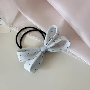 Gros plan d'un chouchou à nœud en tissu bleu clair à pois avec élastiques