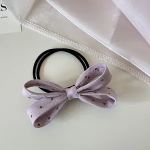 Gros plan d'un chouchou en tissu à pois lavande avec un joli nœud papillon
