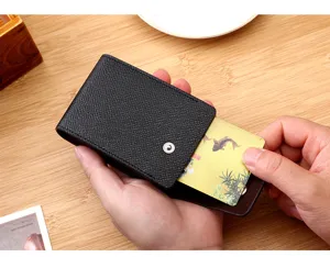 Hand zieht eine Karte aus einem schwarzen strukturierten Leder-Kartenetui auf einem Tisch