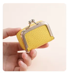 Hand holding a mini yellow genuine leather kiss-lock jewelry and coin storage bag