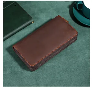 Nahaufnahme einer braunen Vintage-Ledergeldbörse für Herren auf grünem Untergrund.