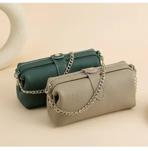 Close-up showing green and taupe pebbled leather toiletry bags with elegant gold chain straps