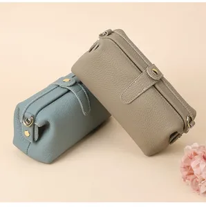 Detailed view of two pebbled cowhide leather cosmetic bags with elegant gold hardware.