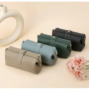 Detailed view of four textured cowhide toiletry bags in khaki, blue, green and black.