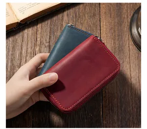 Hand holding vintage red Crazy Horse leather key wallet with rustic wooden background