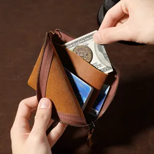 Detailansicht einer Münzbörse aus Crazy-Horse-Leder mit Bargeld und Karten in Hand