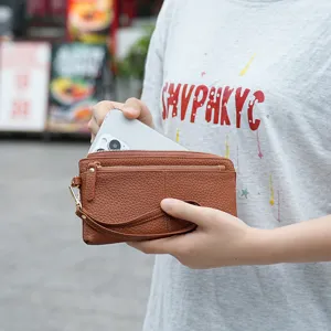 Γυναικείο μακρύ δερμάτινο πορτοφόλι σε καφέ χρώμα με τρία φερμουάρ και λουράκι καρπού.