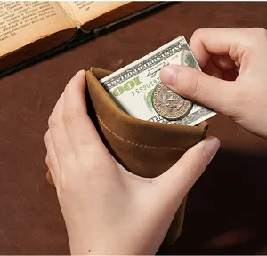 Hand holding a brown crazy horse leather coin pouch showing its capacity for cash.