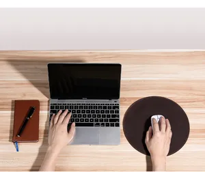 Vue de dessus d'un tapis de souris rond en cuir marron foncé sur un bureau en bois