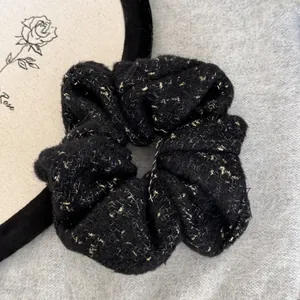Close-up of black fuzzy scrunchie with gold metallic flecks and soft felt texture