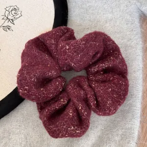 Close-up of a burgundy felt scrunchie with gold sparkles on a fuzzy background.