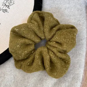 Close-up detail of olive green felt scrunchie with gold sparkles for winter bun hairstyles