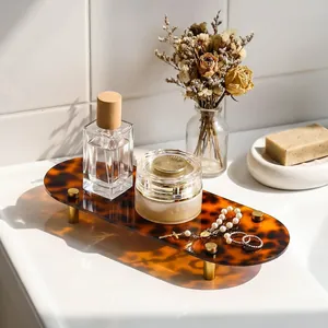 Tortoise shell acrylic tray showcasing perfume and jewelry on a white bathroom vanity