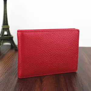 Red pebbled leather driver's license cover on a wooden desk with a mini Eiffel Tower