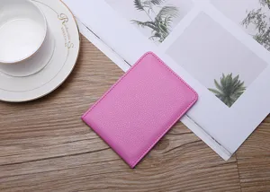 Close-up of pink pebbled leather license holder with visible stitching on wood desk.